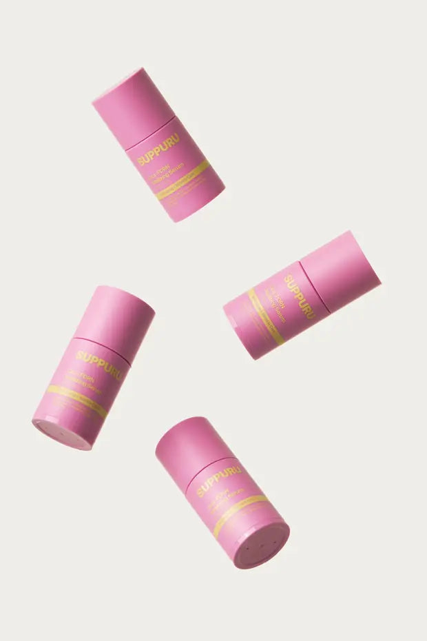 Vier flesjes SUPPURU Cica-PDRN Vitaliserend Serum zwevend boven een licht crème decor in daglicht